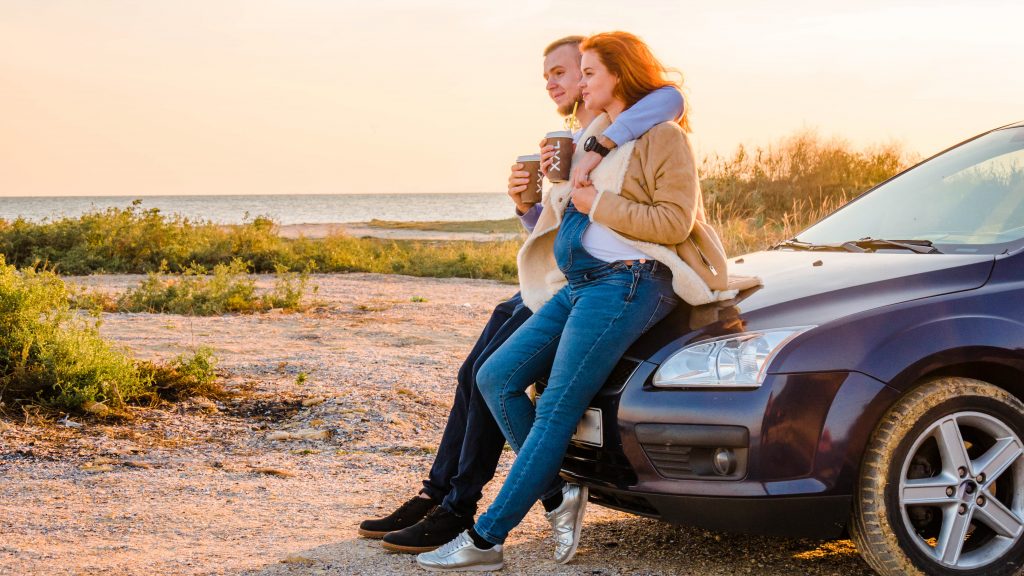 couple sitting on car hood