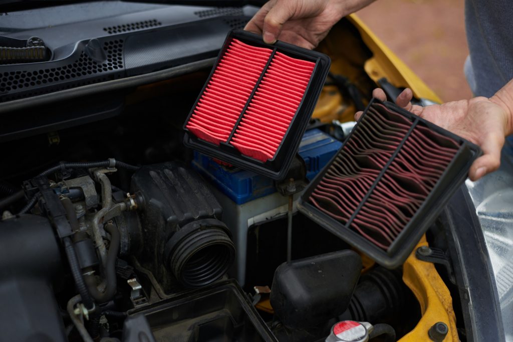 car with person holding old and new filters