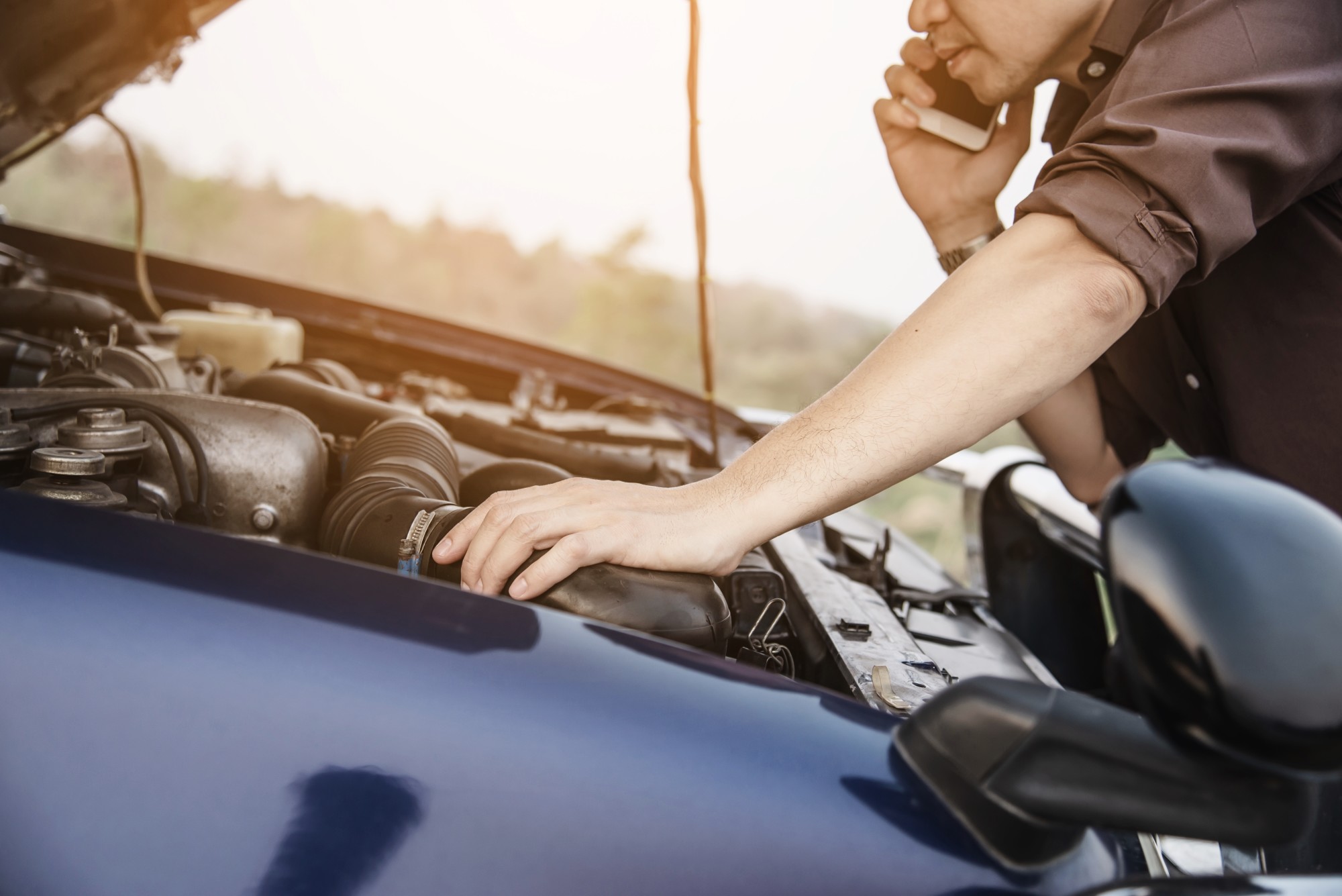 man with phone and broken vehicle