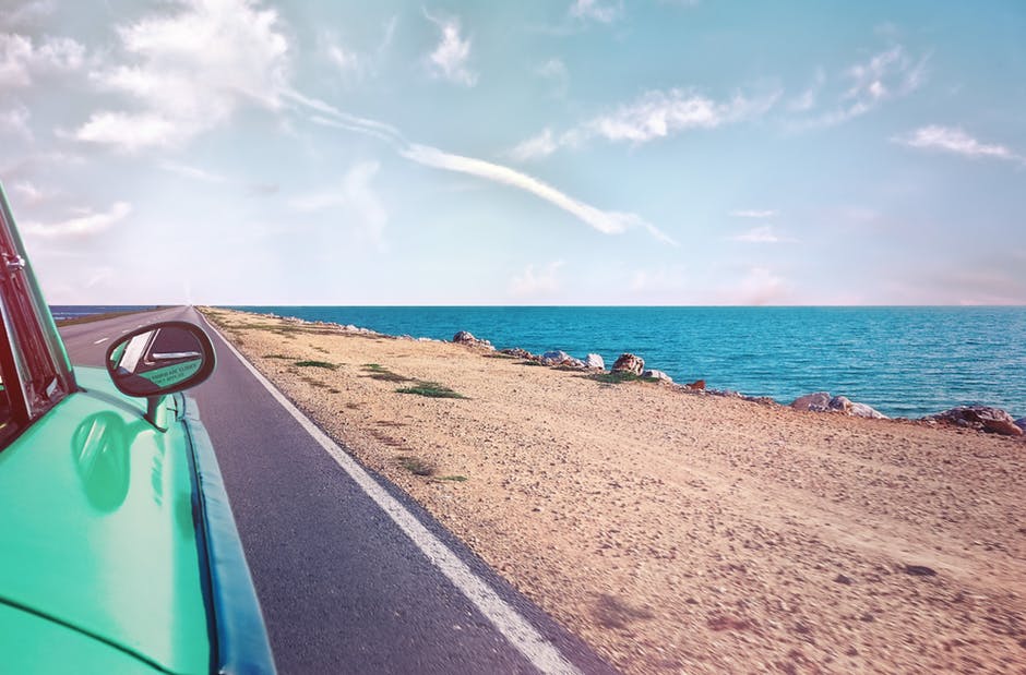 Car Driving on a Paved Road Along a Seashore